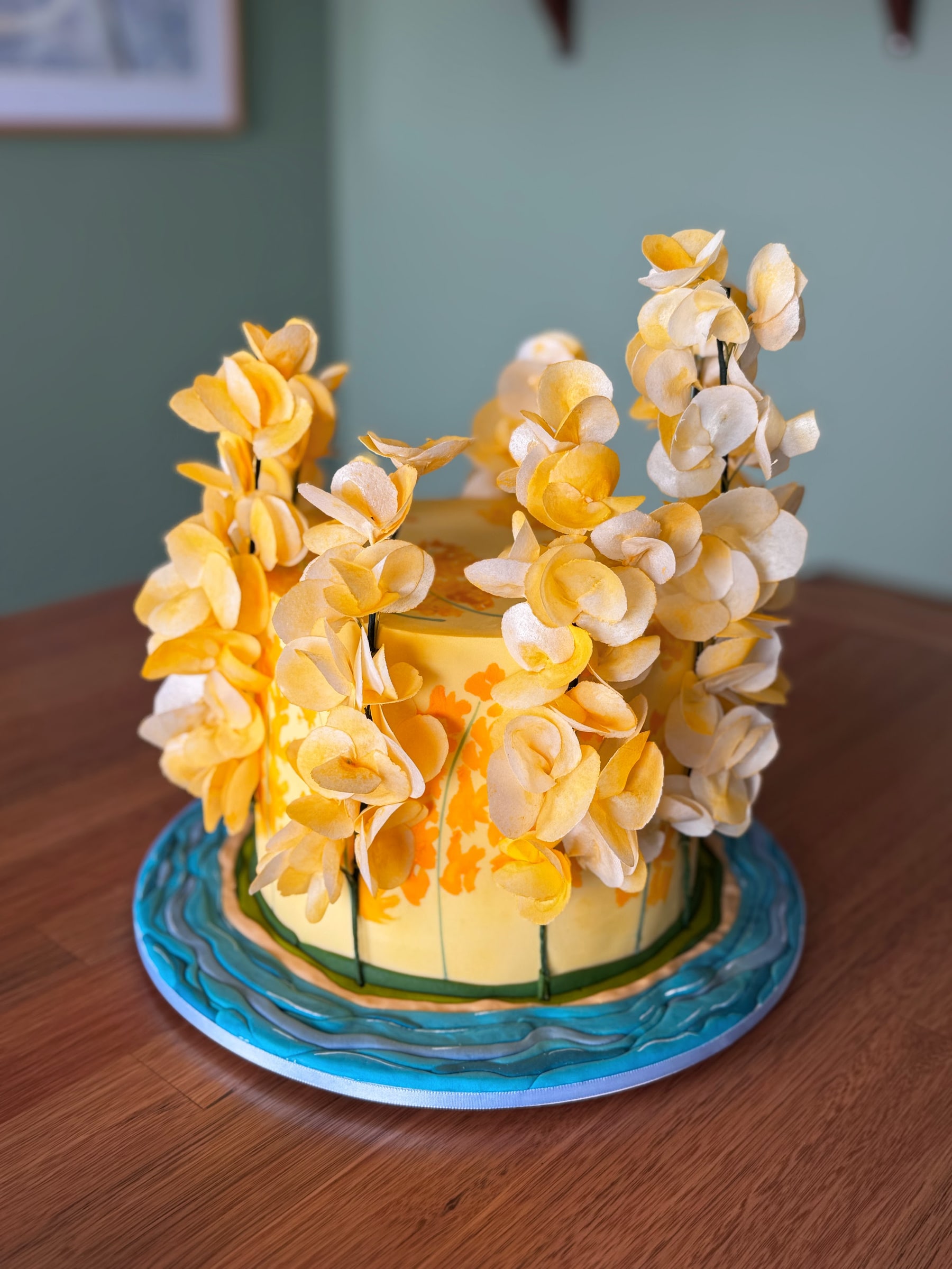 Bolo amarelo com pintura à mão e cascata de flores de wafer paper em tons de amarelo e creme